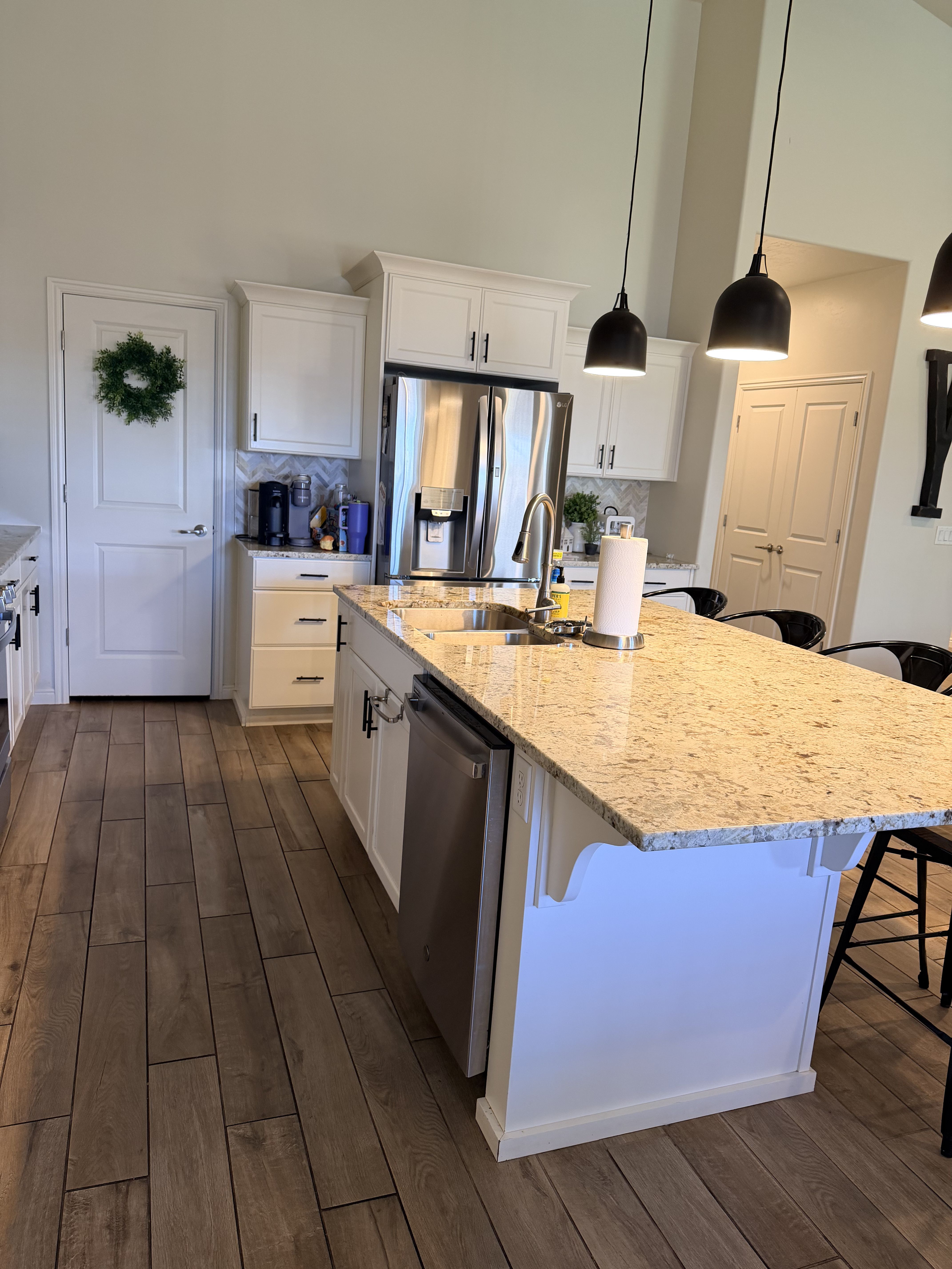 Kitchen featuring white cabinetry, a breakfast bar area, light stone countertops, backsplash, and a high ceiling