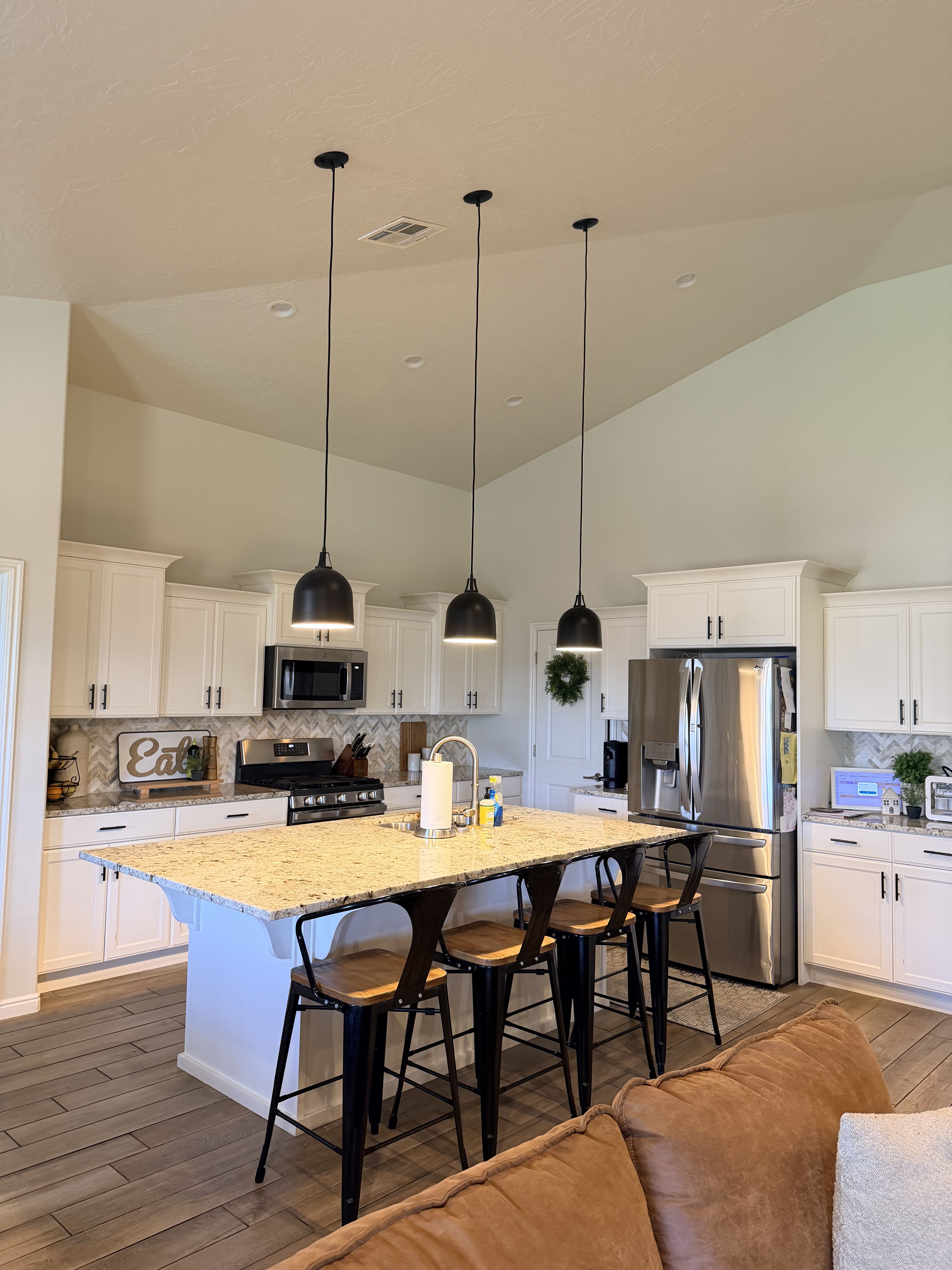 Kitchen featuring tasteful backsplash, dark wood-style floors, white cabinetry, stainless steel appliances, and light stone counters