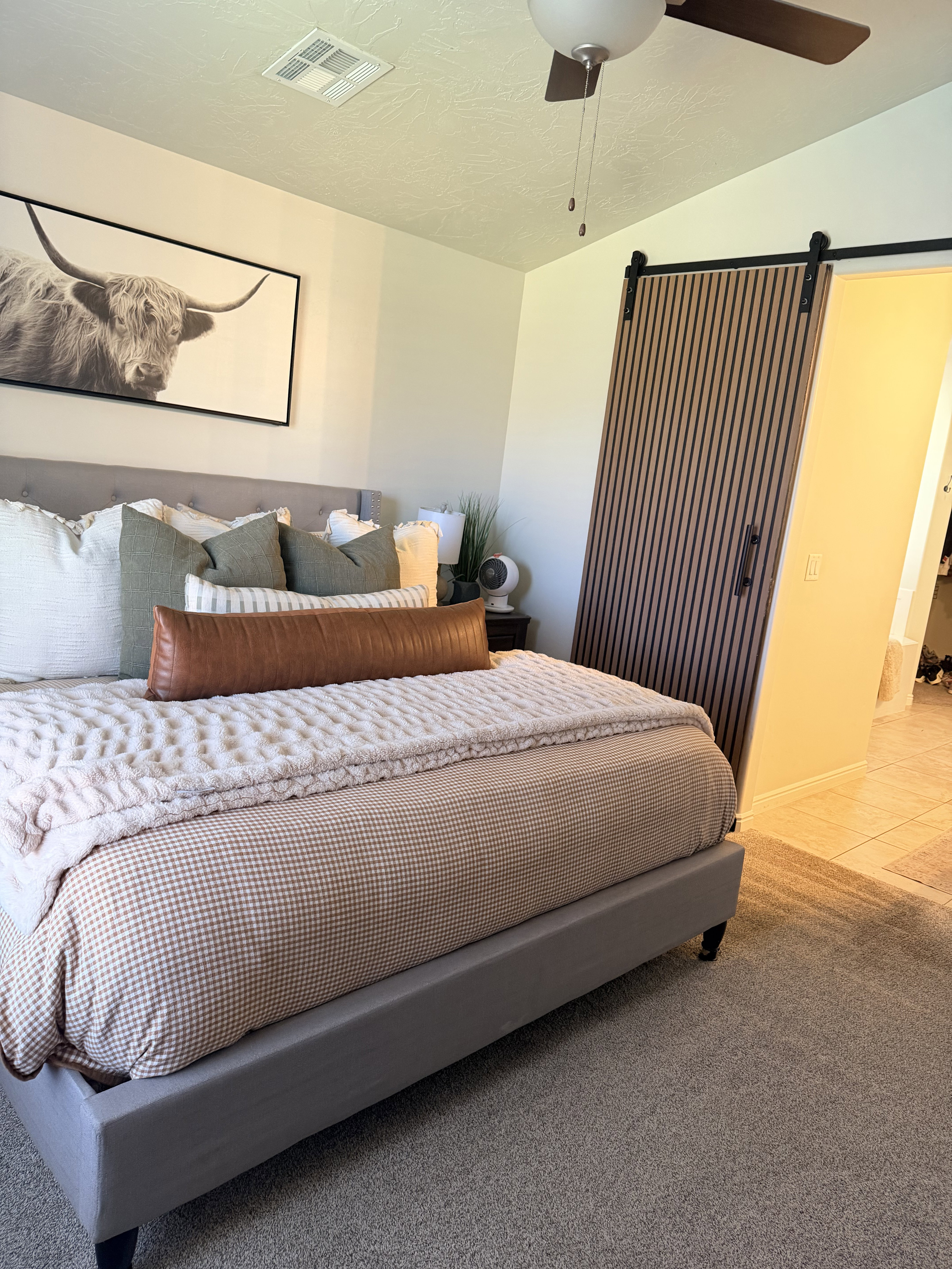 Bedroom with a barn door, light colored carpet, a ceiling fan, and light tile patterned flooring