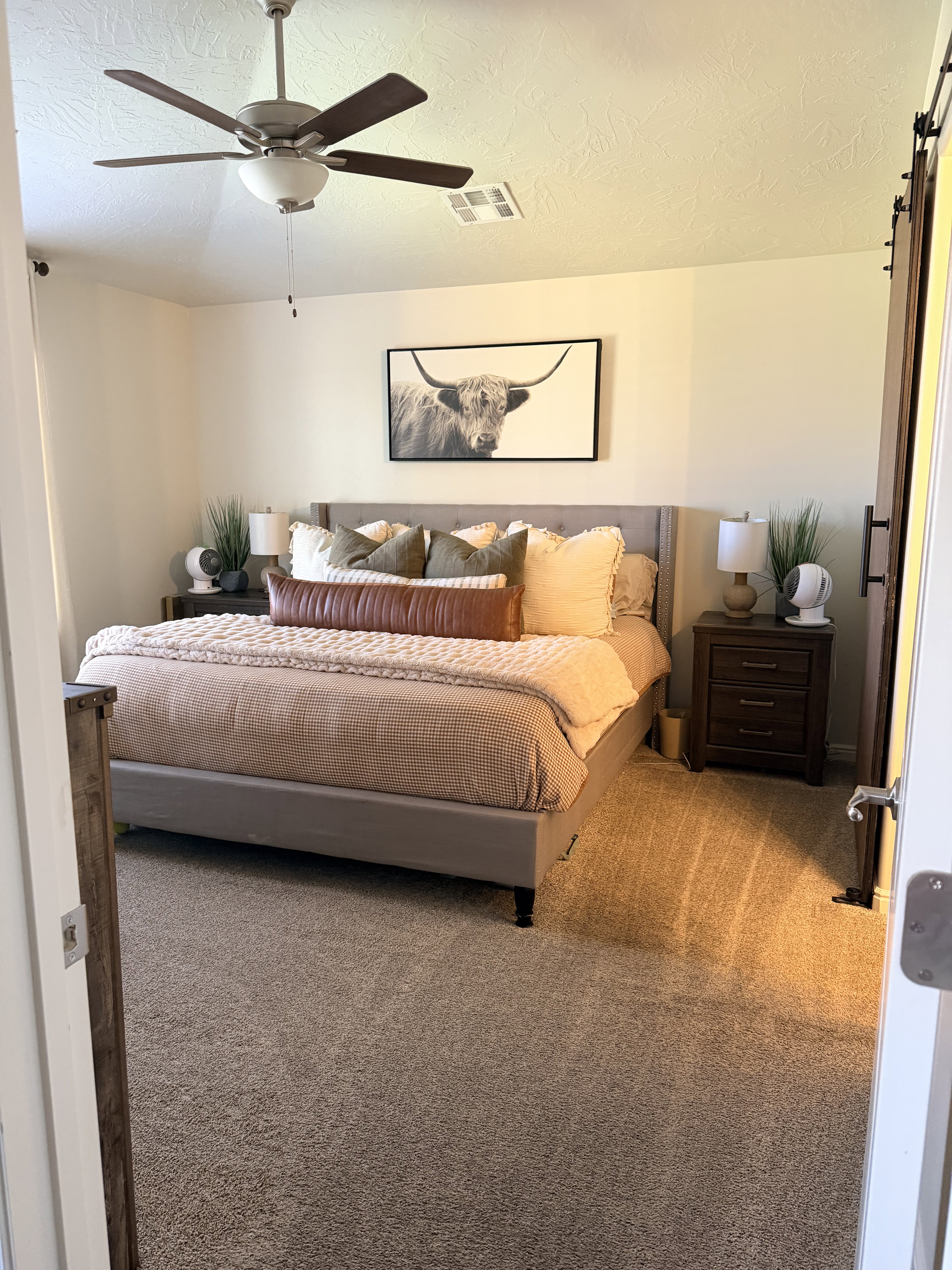 Carpeted bedroom featuring a textured ceiling, a barn door, and a ceiling fan