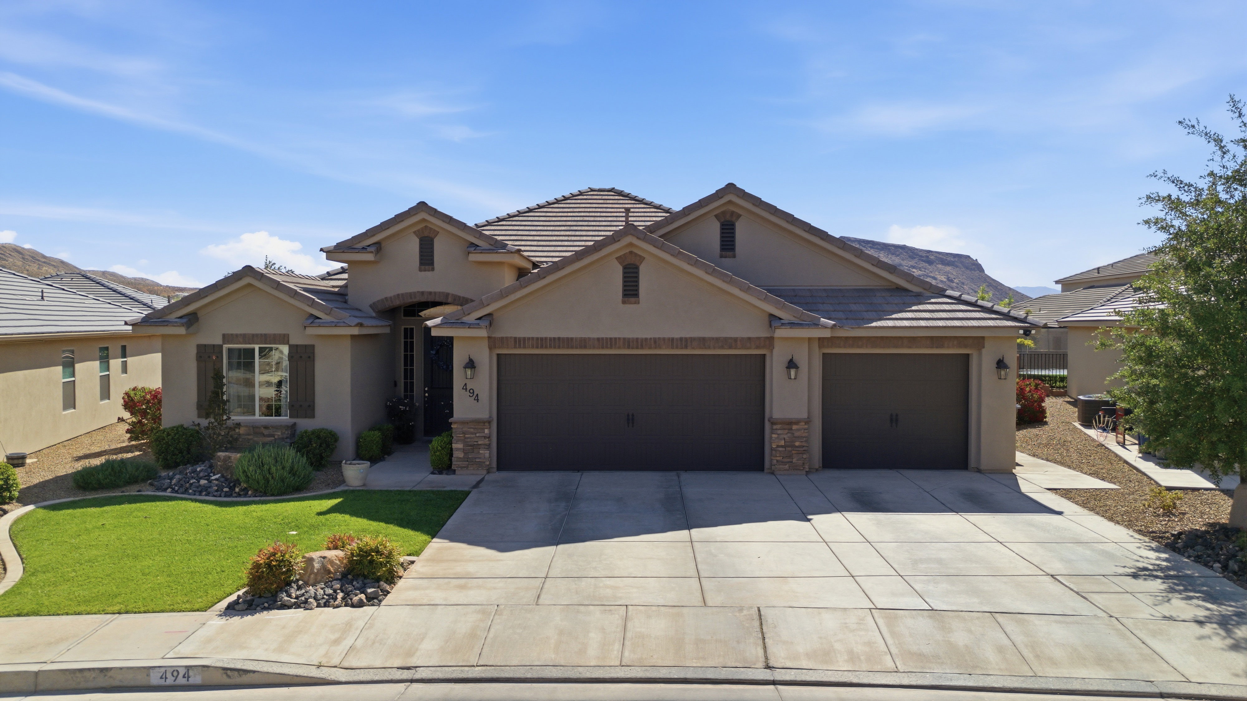 Stucco exterior residence with a tile roof, featuring a two-car garage, a one-car garage, and a concrete driveway
