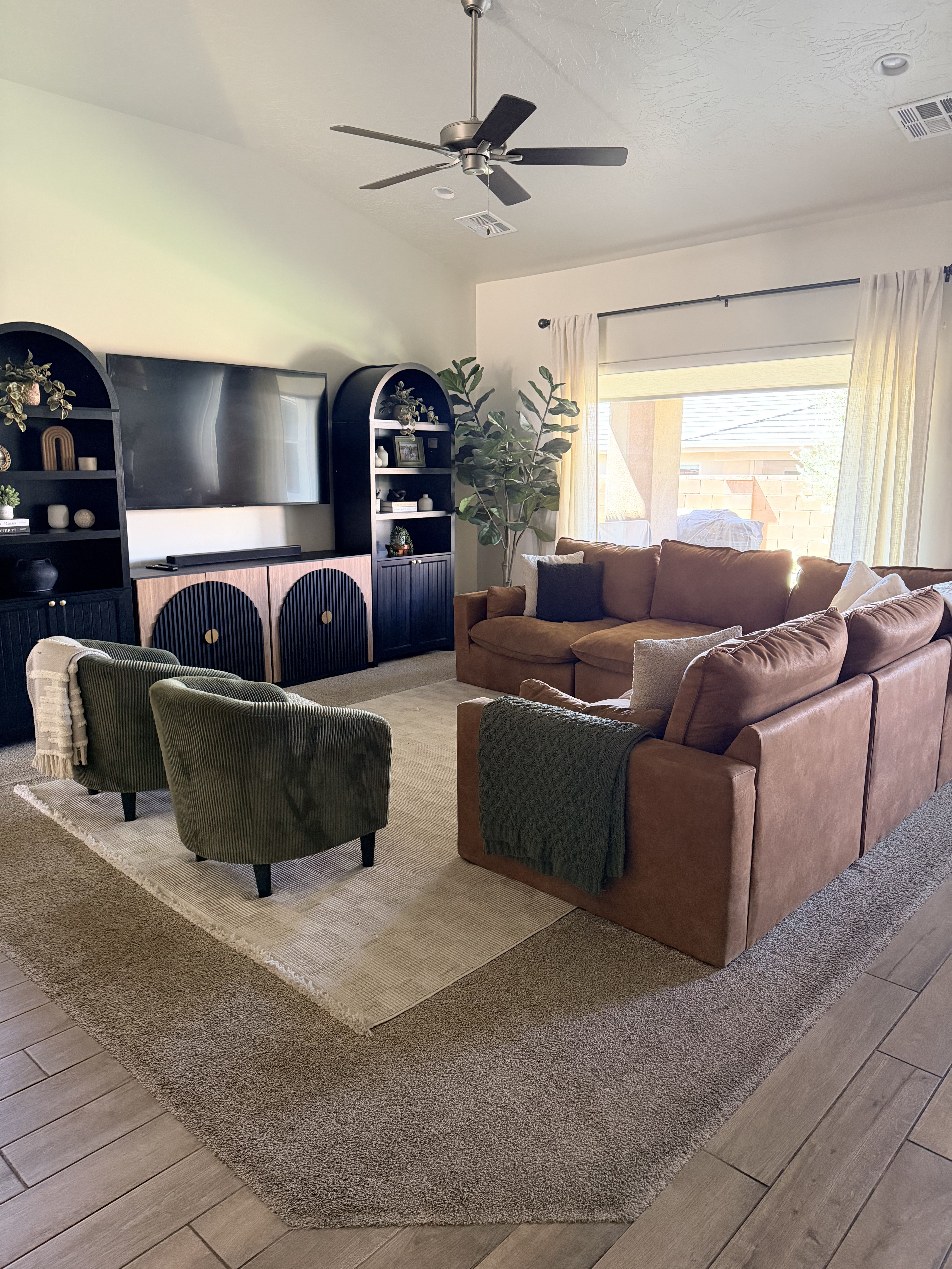 Living room with built in features, wood finish floors, a ceiling fan, and lofted ceiling