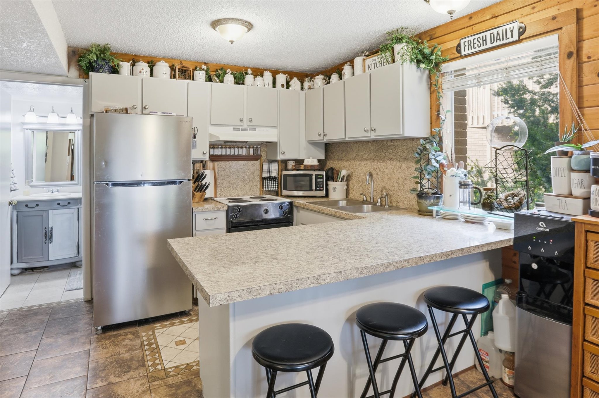 Kitchen featuring a breakfast bar, stainless steel appliances, a peninsula, light countertops, and tasteful backsplash