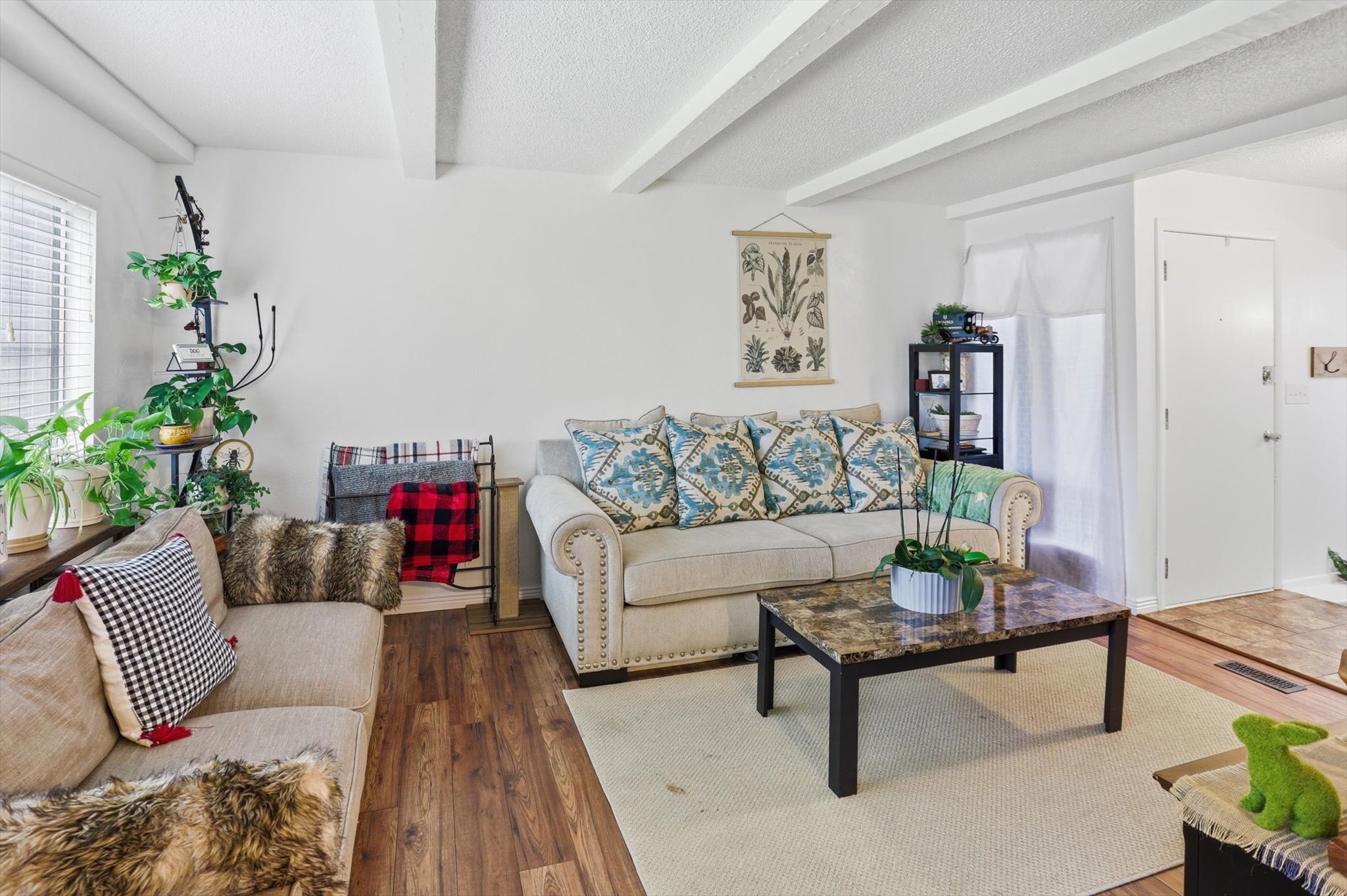 Living room featuring a textured ceiling, hardwood / wood-style flooring, and beamed ceiling