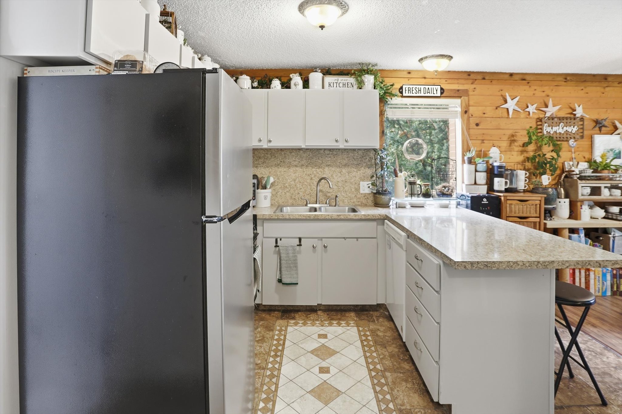 Kitchen featuring a peninsula, freestanding refrigerator, a kitchen breakfast bar, light countertops, and a textured ceiling