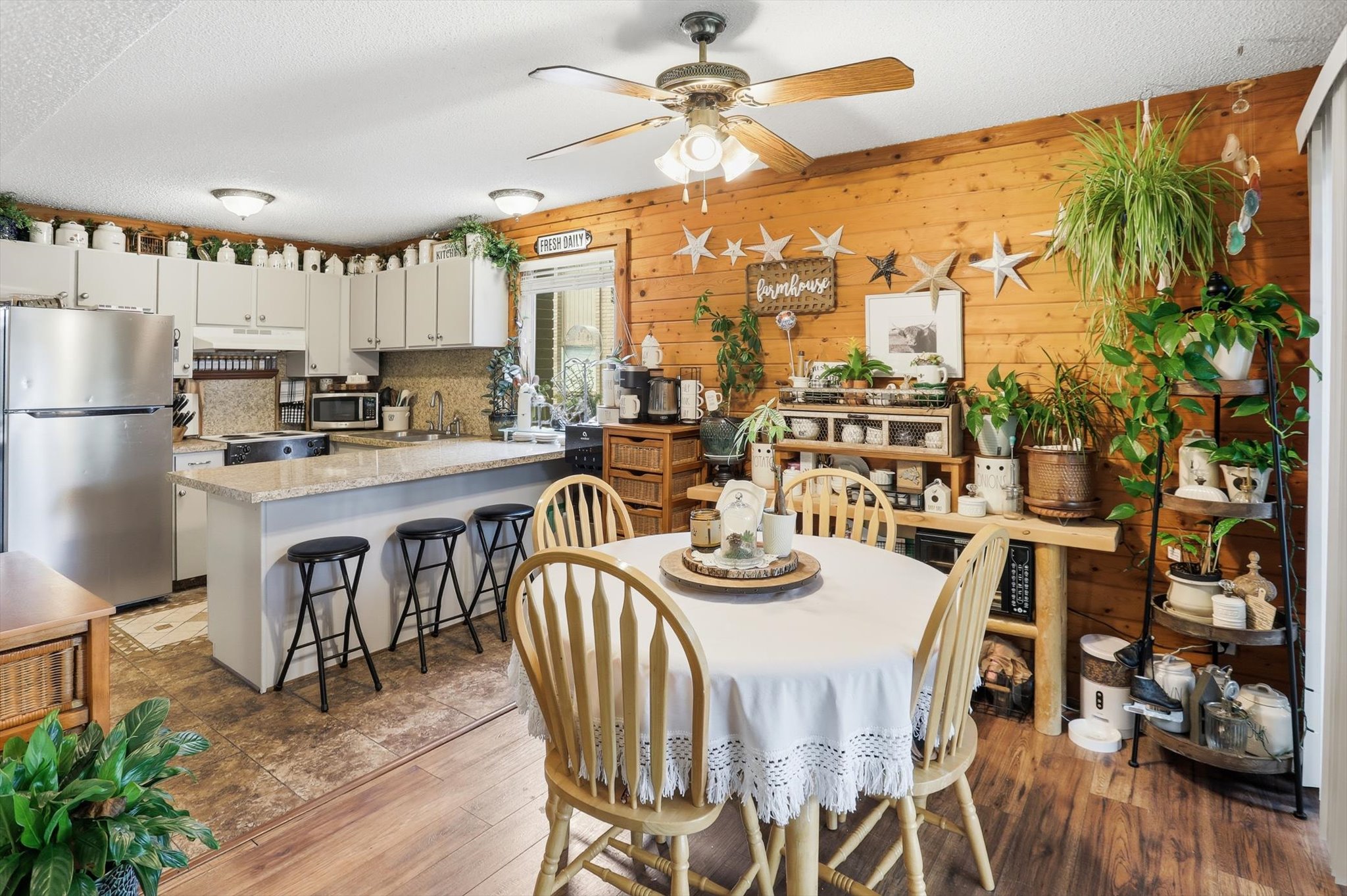 Dining area with a ceiling fan, wood walls, and a textured ceiling