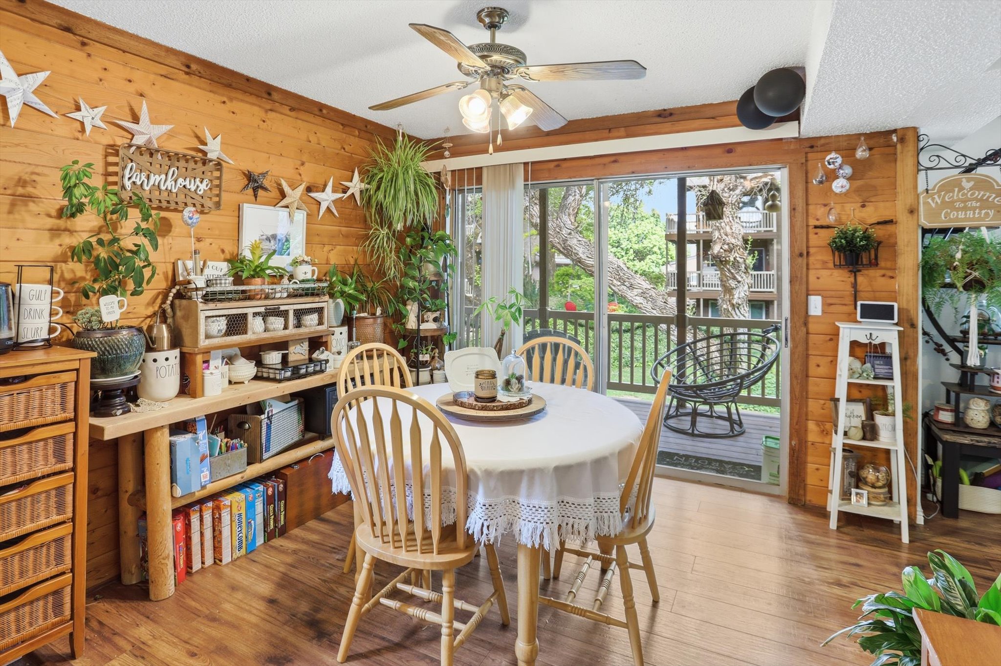 Dining space with wooden walls, a textured ceiling, ceiling fan, and wood-type flooring