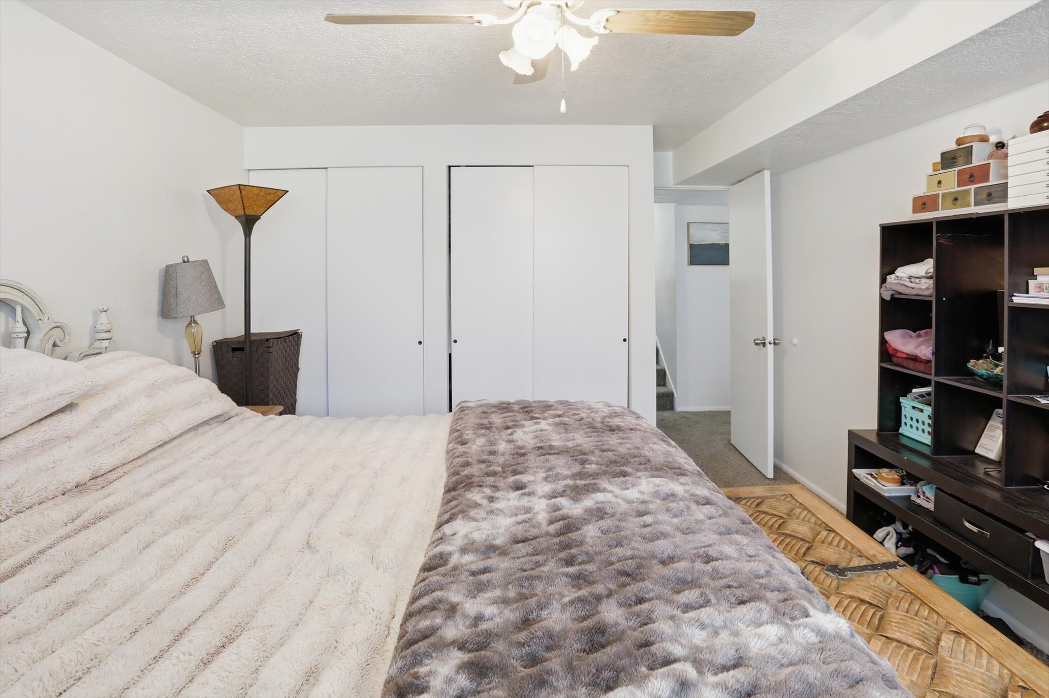 Bedroom featuring two closets, a textured ceiling, ceiling fan, and light carpet