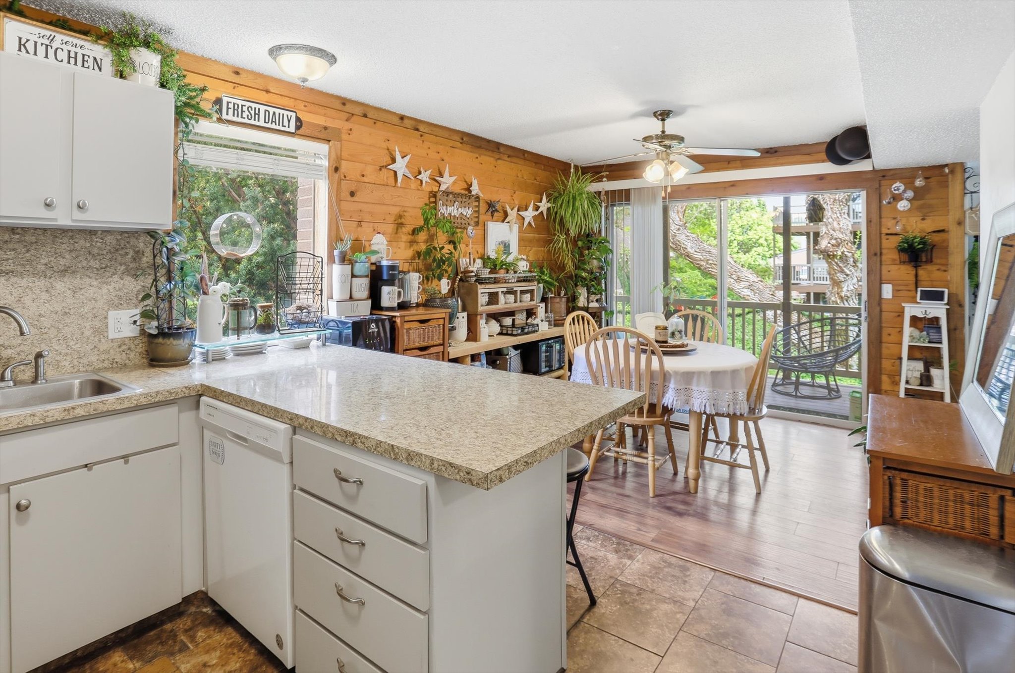 Kitchen featuring a peninsula, wooden walls, white cabinets, and light countertops