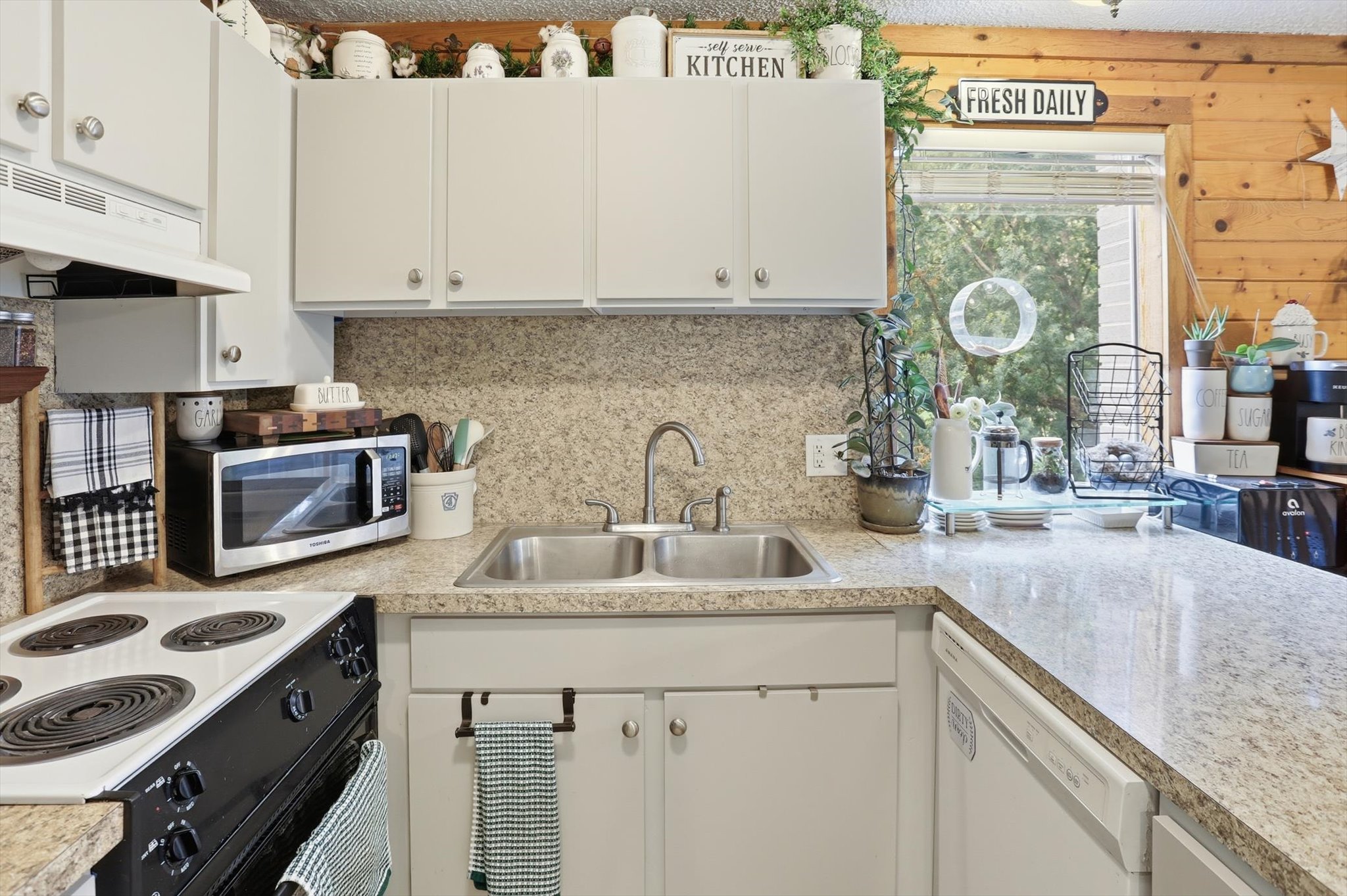 Kitchen with light countertops, range with electric stovetop, white cabinets, and stainless steel microwave