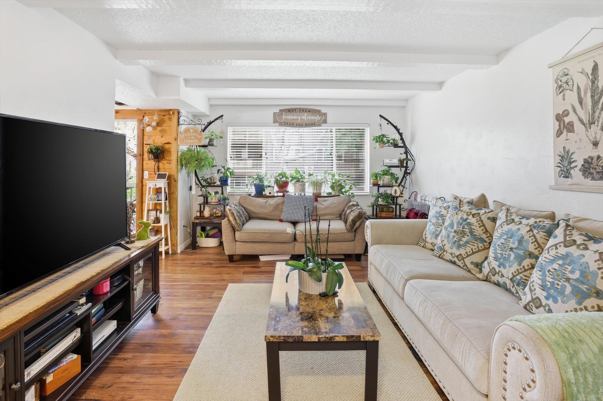 Living area featuring beamed ceiling, wood finished floors, a textured ceiling, and hanging lights