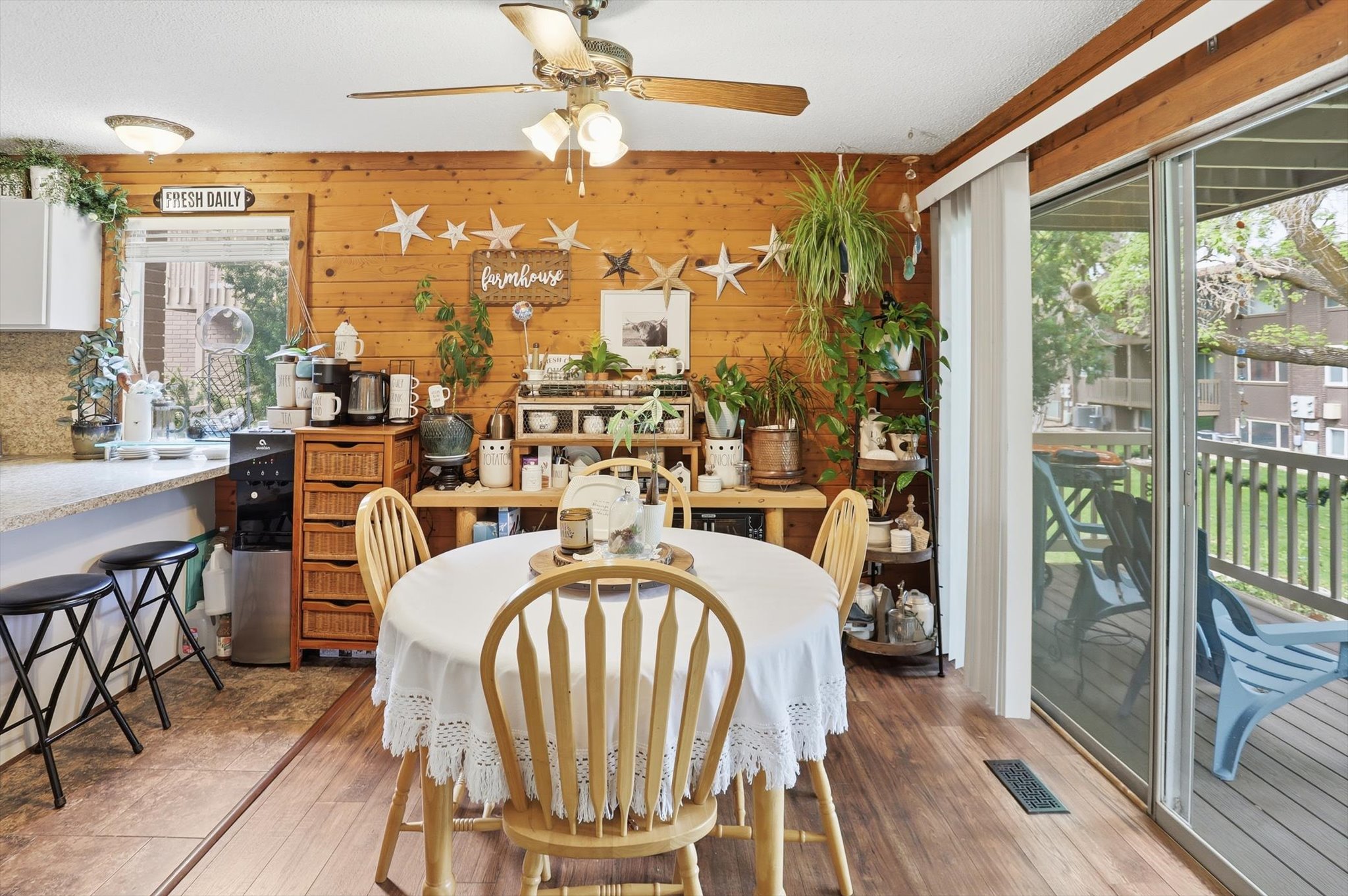 Dining area with ceiling fan, wooden walls, and wood finished floors