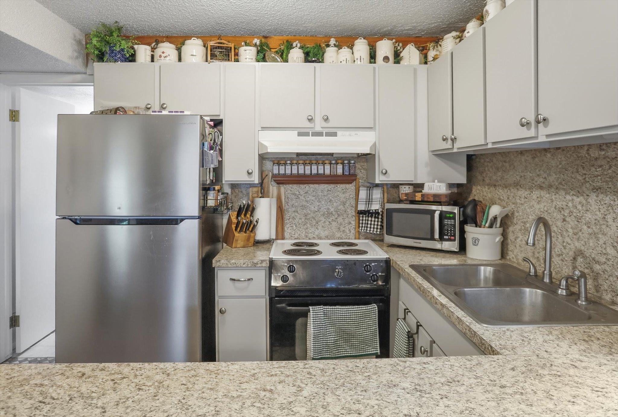 Kitchen with stainless steel appliances, light countertops, a textured ceiling, and decorative backsplash