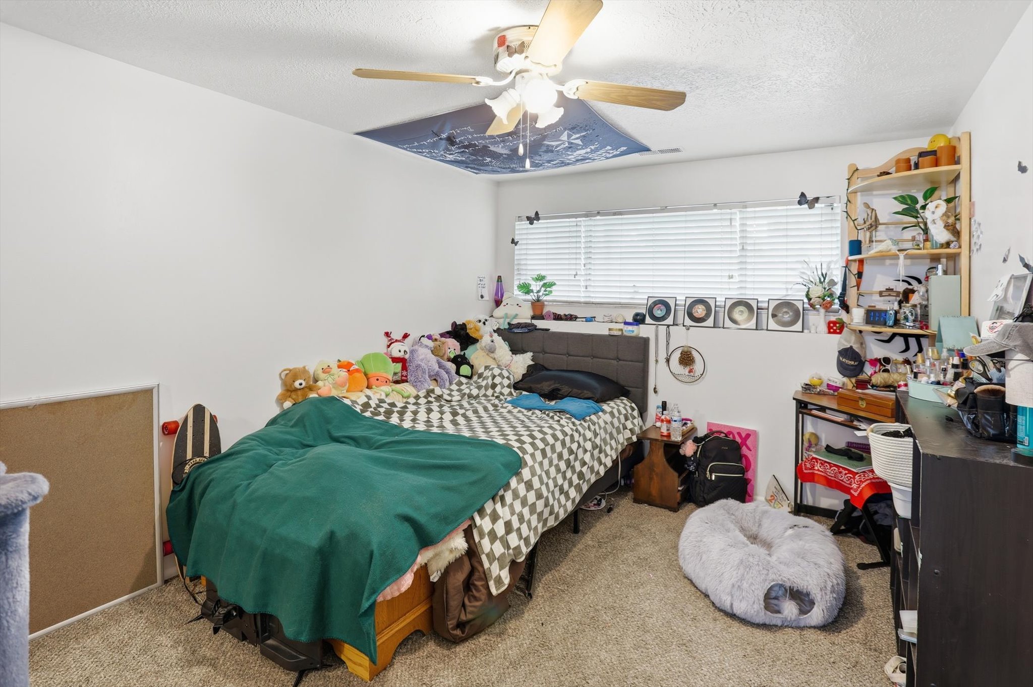 Carpeted bedroom with a textured ceiling and ceiling fan