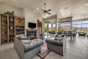 Living room featuring ceiling fan, recessed lighting, a high end fireplace, a high ceiling, and light tile patterned floors