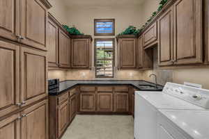 Laundry area featuring washer and clothes dryer, cabinet space, and light tile patterned flooring