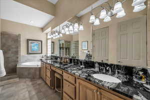 Bathroom with a shower stall, a bath, double vanity, dark tile patterned flooring, and a chandelier