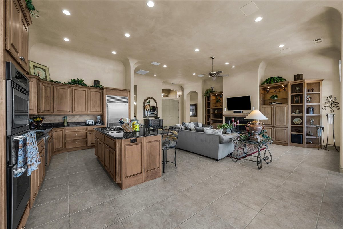 Kitchen featuring arched walkways, wood finish cabinets, open floor plan, dark stone countertops, and a breakfast bar area