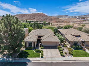 View of front of property with a garage, concrete driveway, a front lawn, and a mountain view