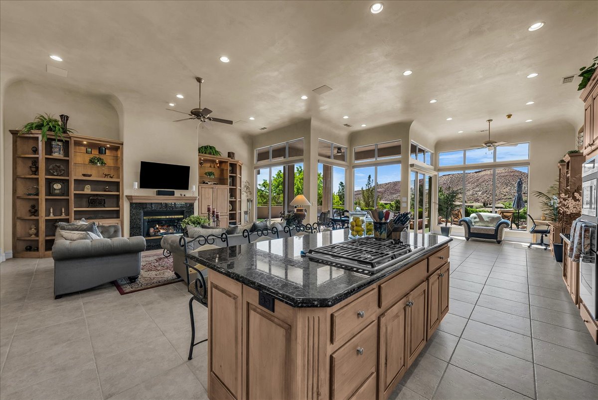 Kitchen featuring a glass covered fireplace, ceiling fan, open floor plan, recessed lighting, and a high ceiling