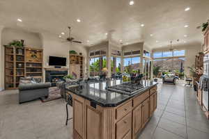 Kitchen featuring a glass covered fireplace, ceiling fan, open floor plan, recessed lighting, and a high ceiling