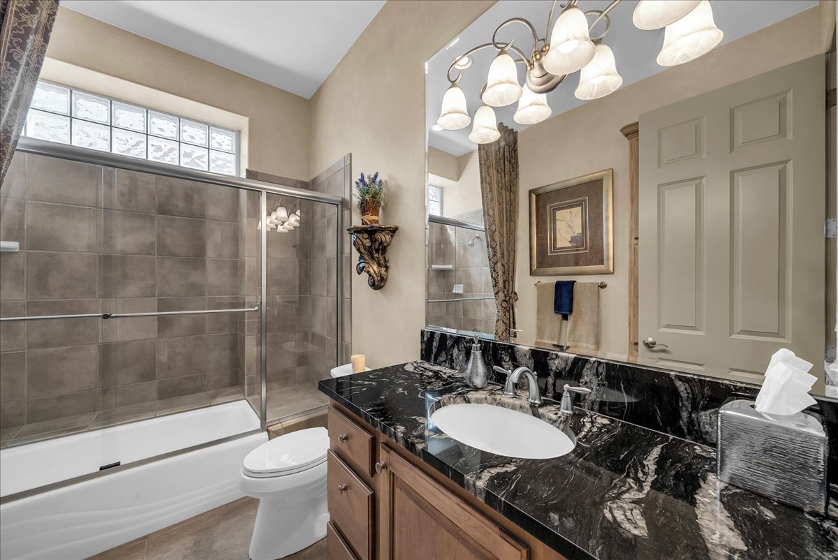 Full bathroom featuring vanity, healthy amount of natural light, shower / bath combination with glass door, and a chandelier