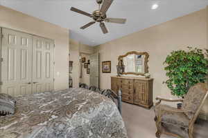 Bedroom with light carpet, ceiling fan, a closet, and recessed lighting