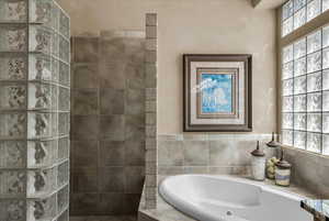 Bathroom featuring plenty of natural light, walk in shower, and a whirlpool tub