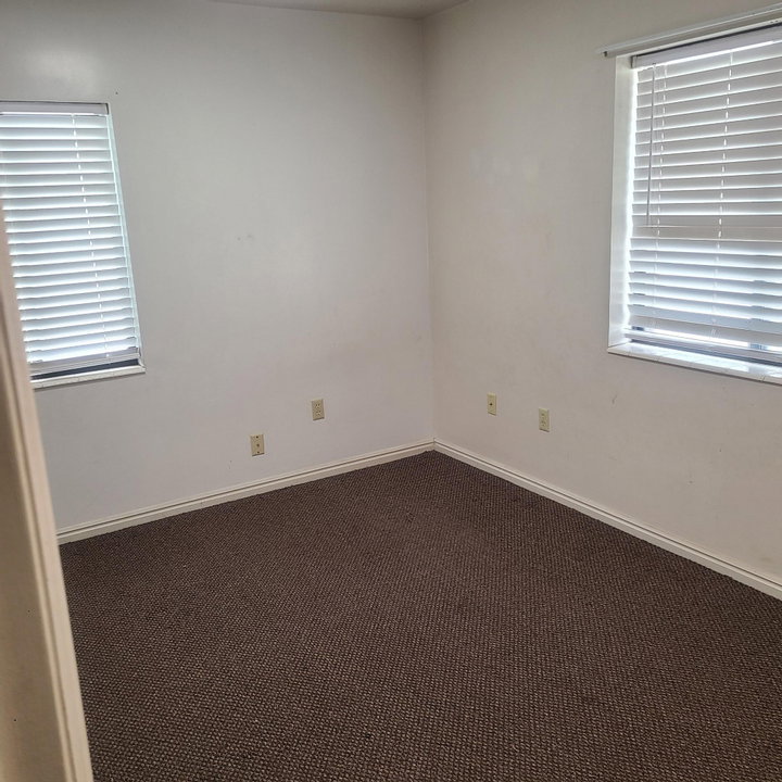Empty room with dark carpet and plenty of natural light
