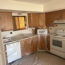 Kitchen featuring white appliances, wood finish cabinets, range hood, and light countertops