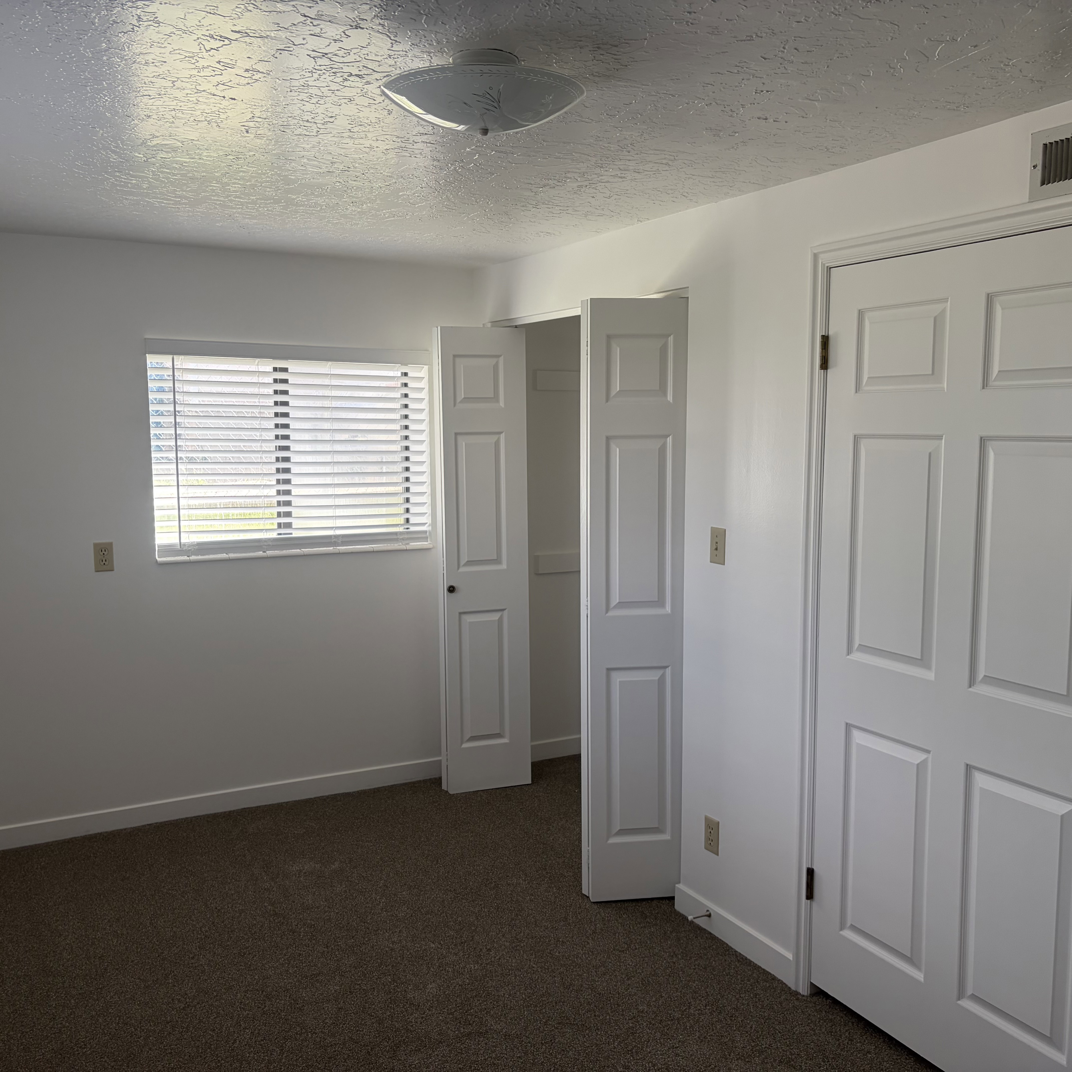 Unfurnished bedroom with a textured ceiling and dark carpet