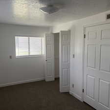 Unfurnished bedroom with a textured ceiling and dark carpet