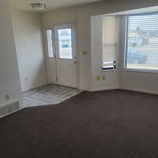 Entrance foyer with light colored carpet and light tile patterned flooring