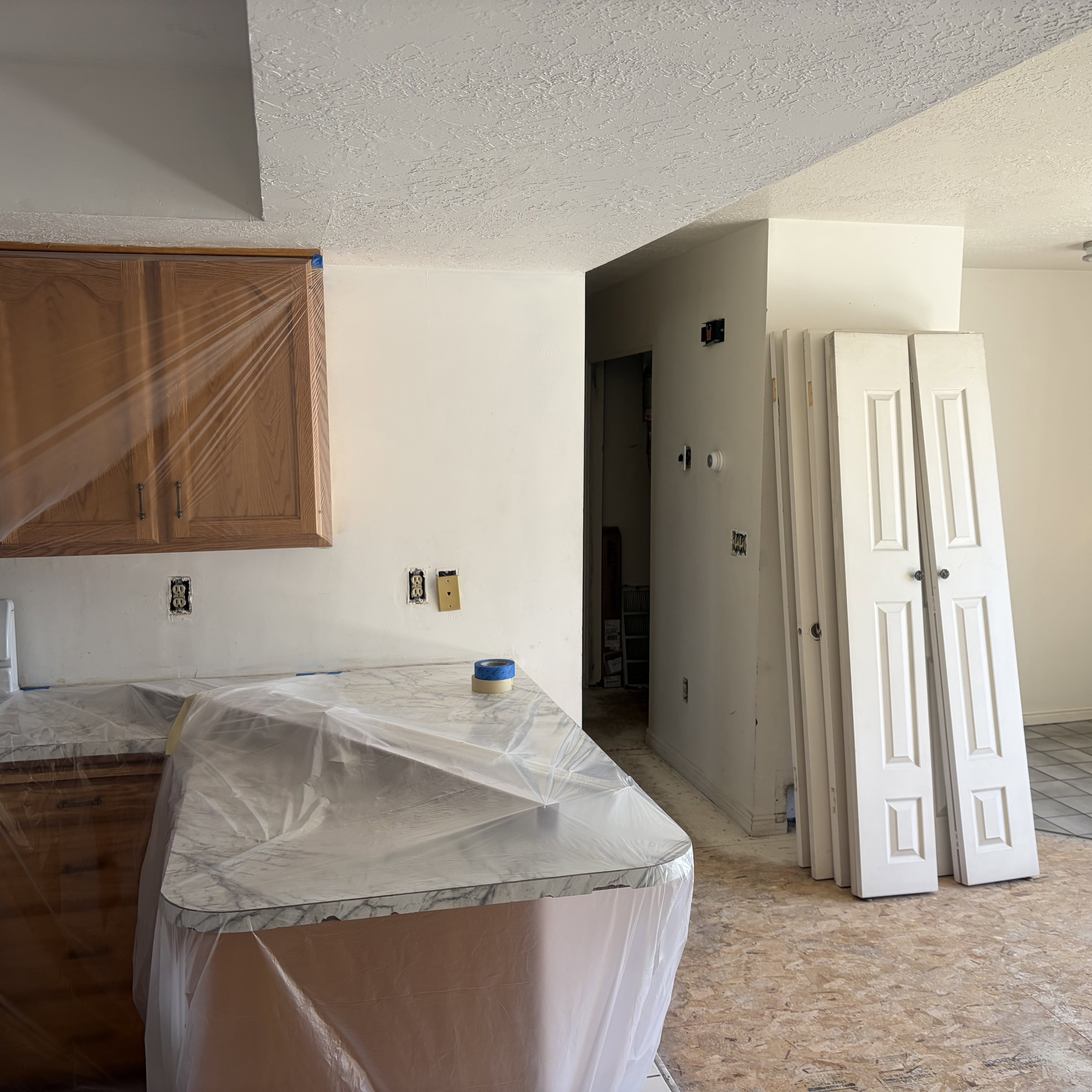 Kitchen with a textured ceiling, light countertops, a peninsula, and wood finish cabinets