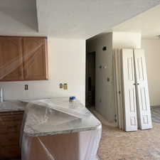 Kitchen with a textured ceiling, light countertops, a peninsula, and wood finish cabinets
