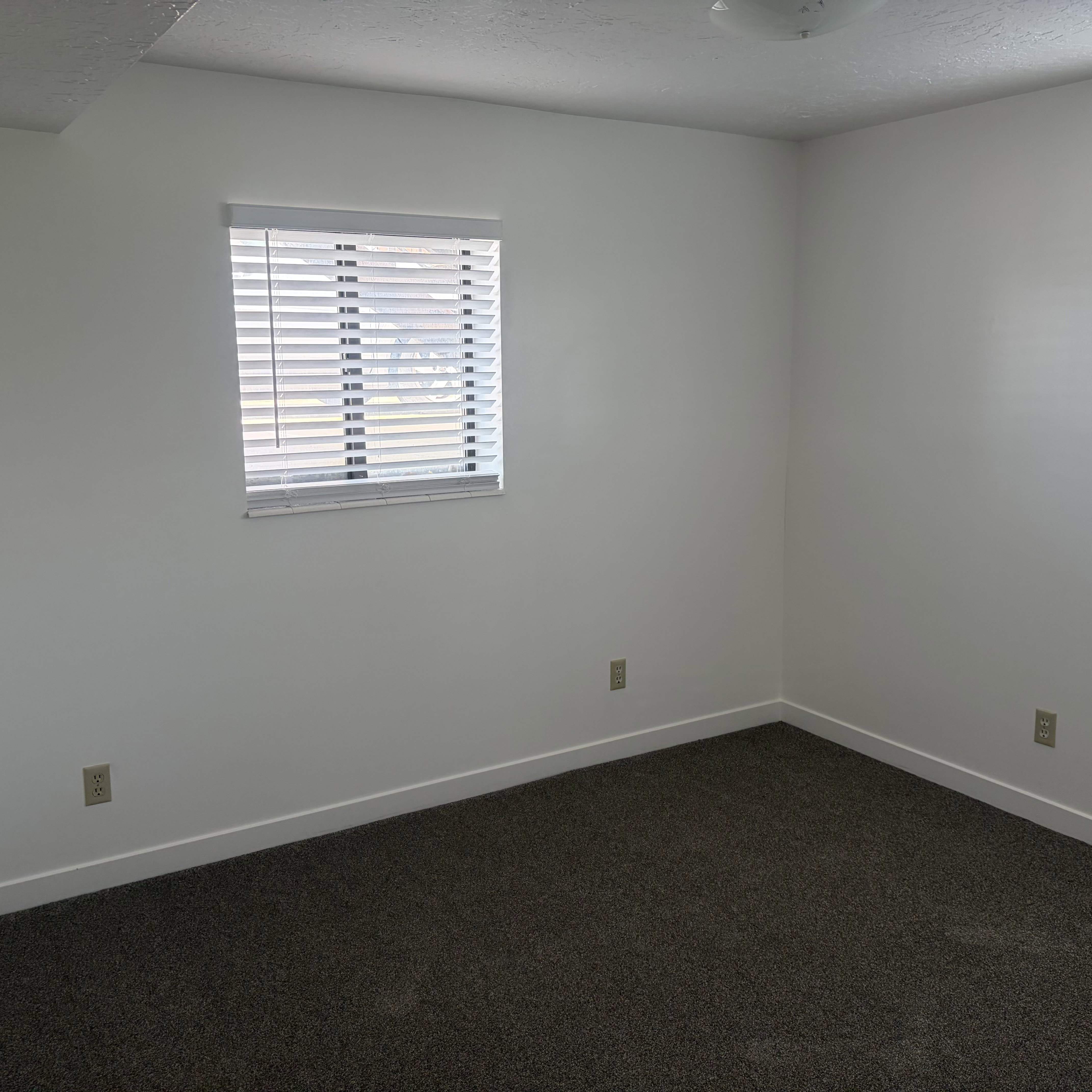 Empty room featuring dark carpet and a textured ceiling