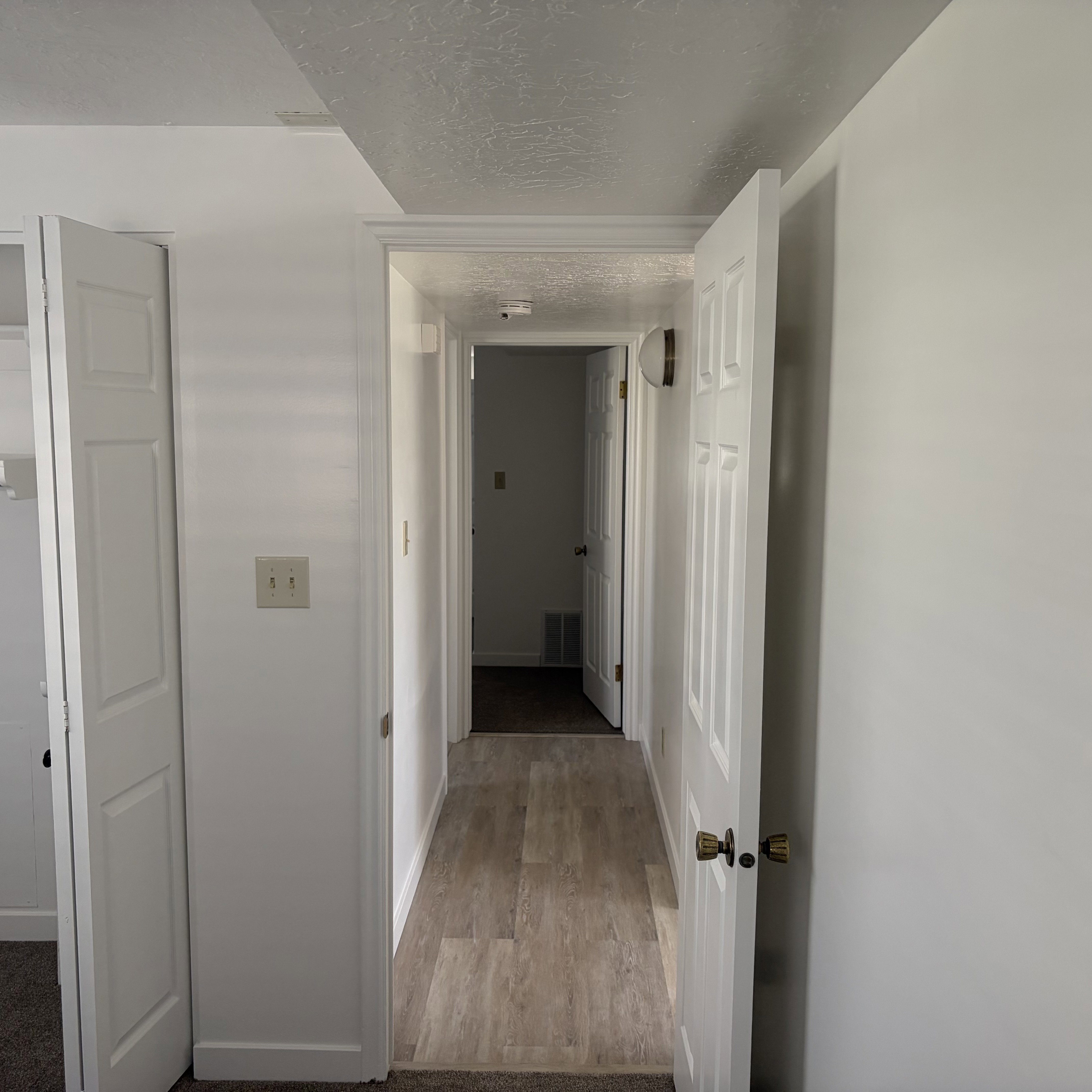 Hallway featuring a textured ceiling and light wood-style flooring