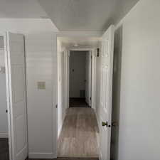 Hallway featuring a textured ceiling and light wood-style flooring
