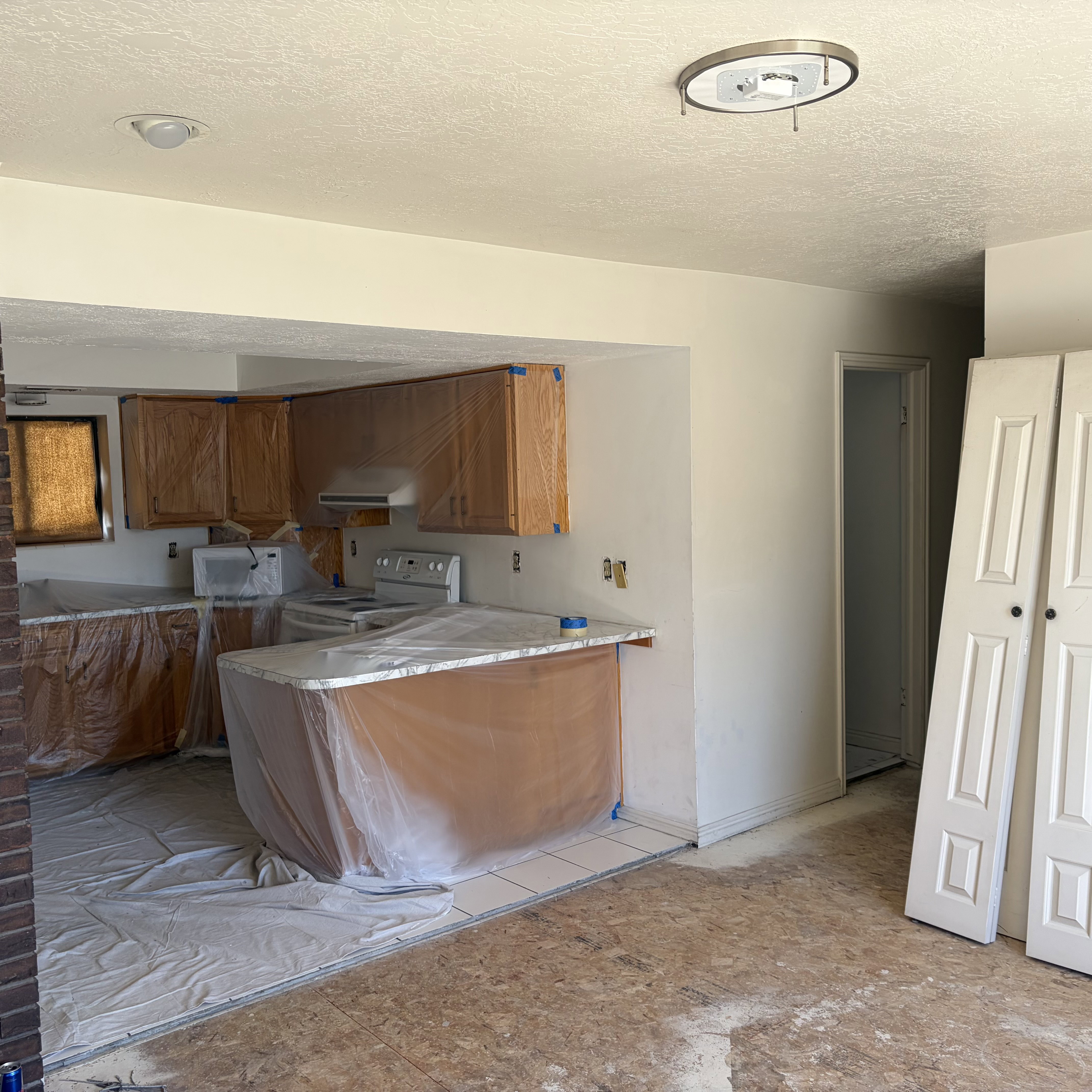 Kitchen with a peninsula, wood finish cabinetry, light countertops, a textured ceiling, and white appliances