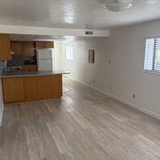 Kitchen with wood finish cabinets, a peninsula, freestanding refrigerator, a textured ceiling, and light wood-style floors