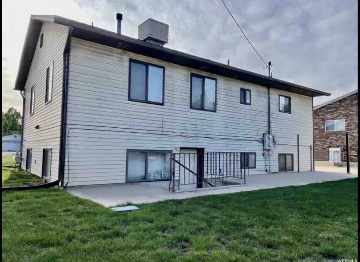 Rear view of property with a lawn and a patio area