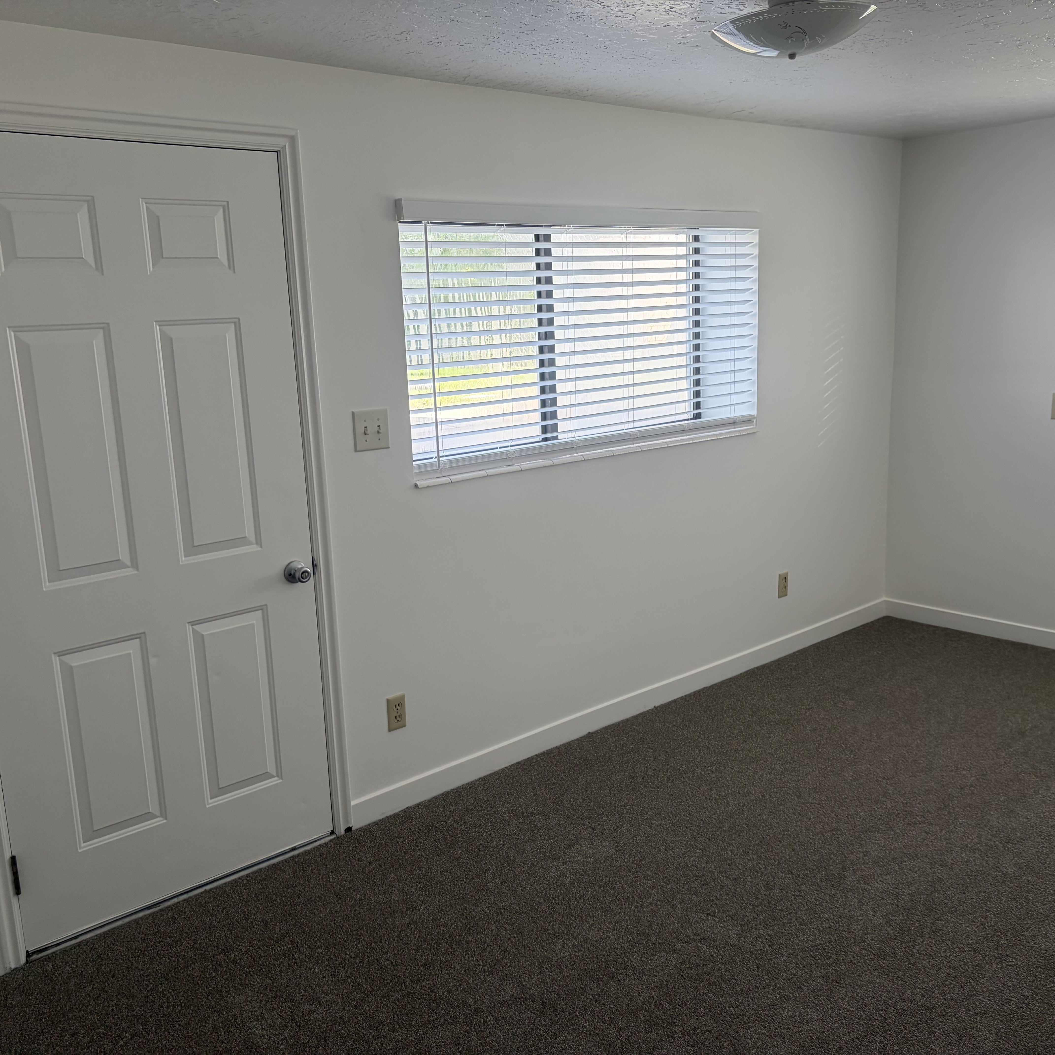 Spare room featuring dark colored carpet and a textured ceiling