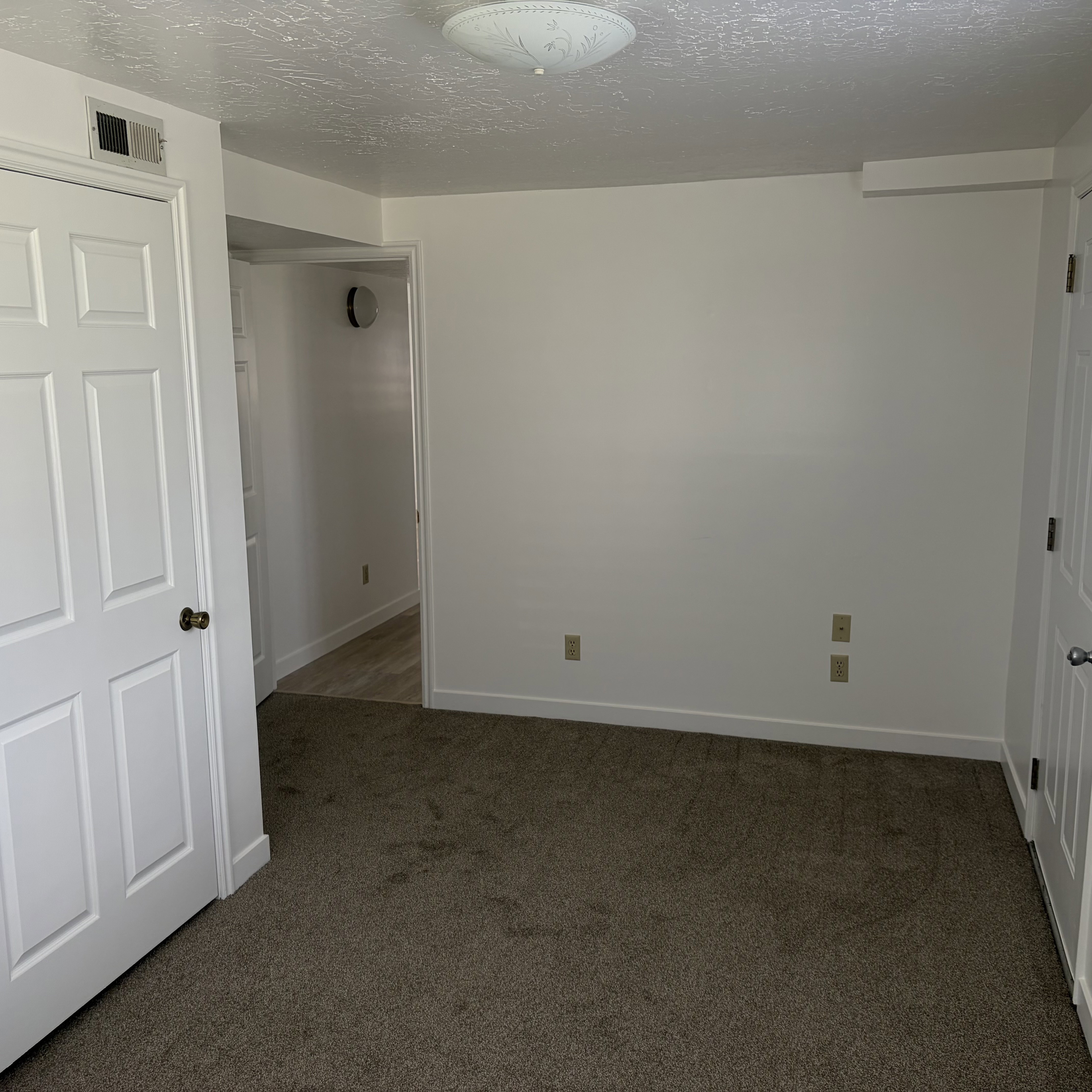 Unfurnished bedroom featuring dark carpet and a textured ceiling