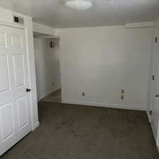 Unfurnished bedroom featuring dark carpet and a textured ceiling