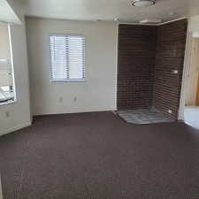 Unfurnished room with dark colored carpet, a textured ceiling, and brick wall