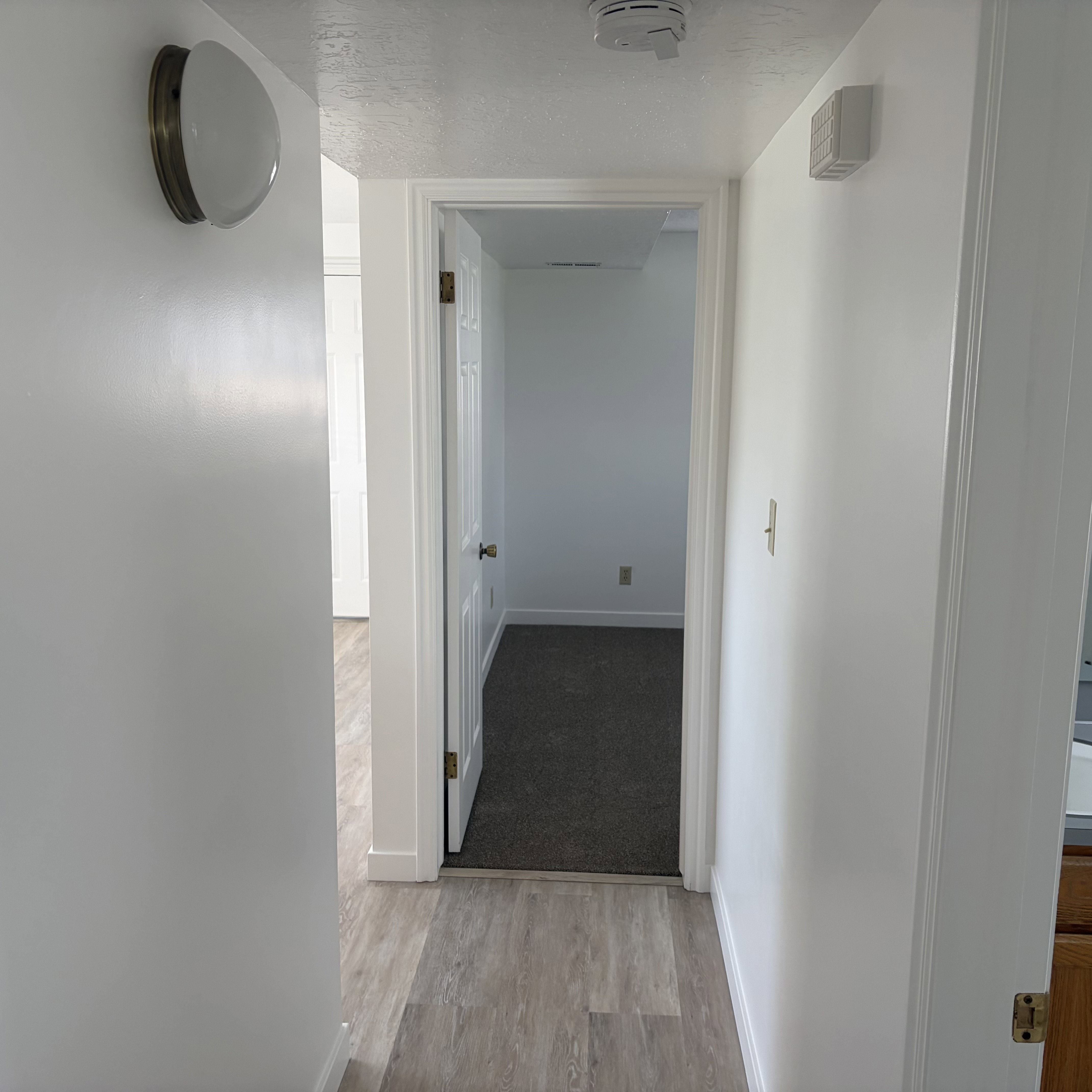 Corridor featuring a textured ceiling and light wood finished floors