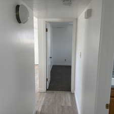 Corridor featuring a textured ceiling and light wood finished floors