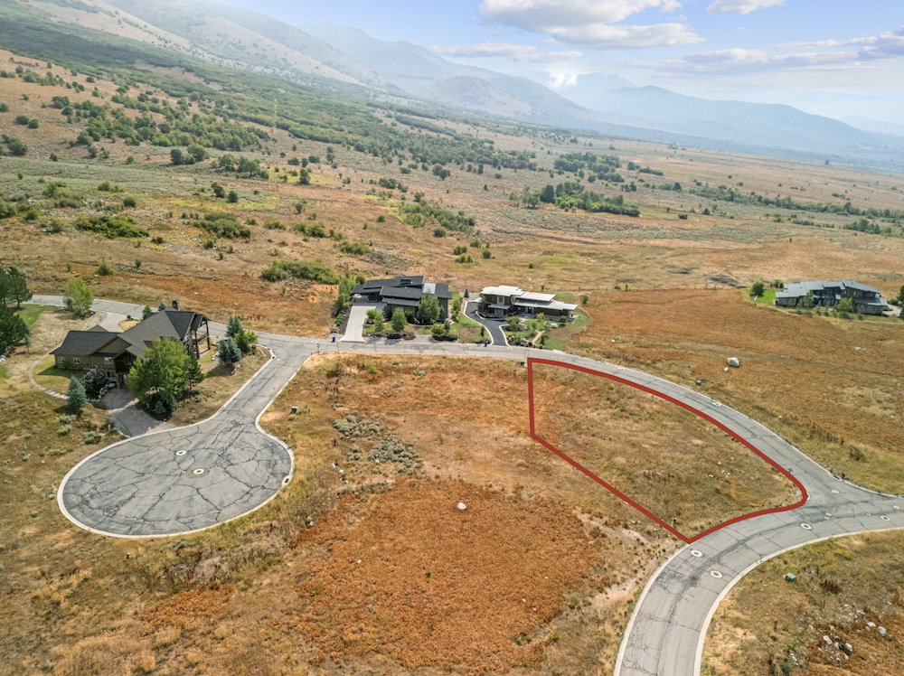 Cleared land parcel outlined in red, featuring a paved road frontage