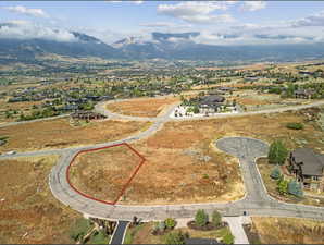 Expansive land parcel featuring existing paved road access, a gentle slope, and a surrounding mountainous landscape