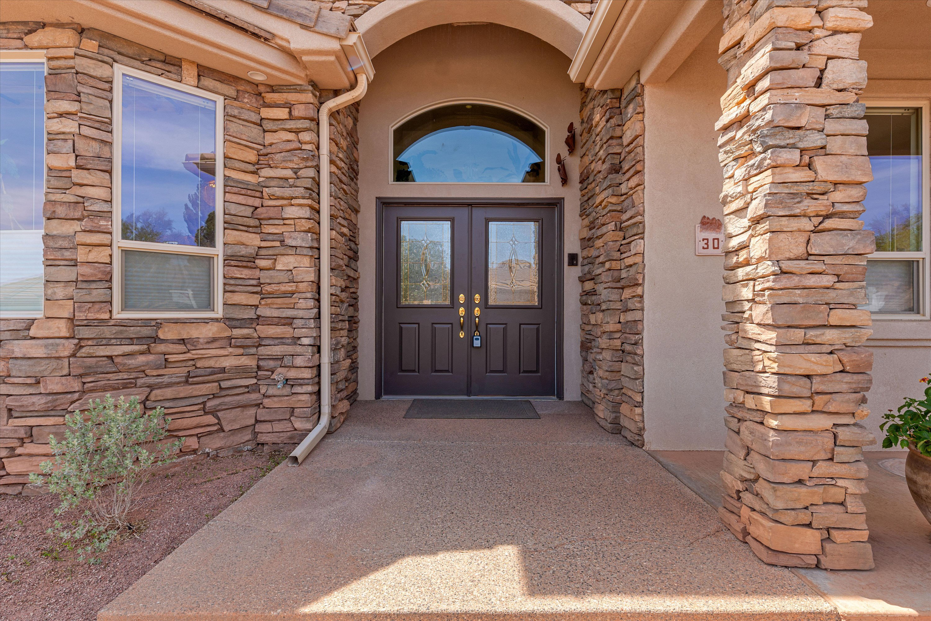 Property entrance with stone siding, stucco siding, and french doors